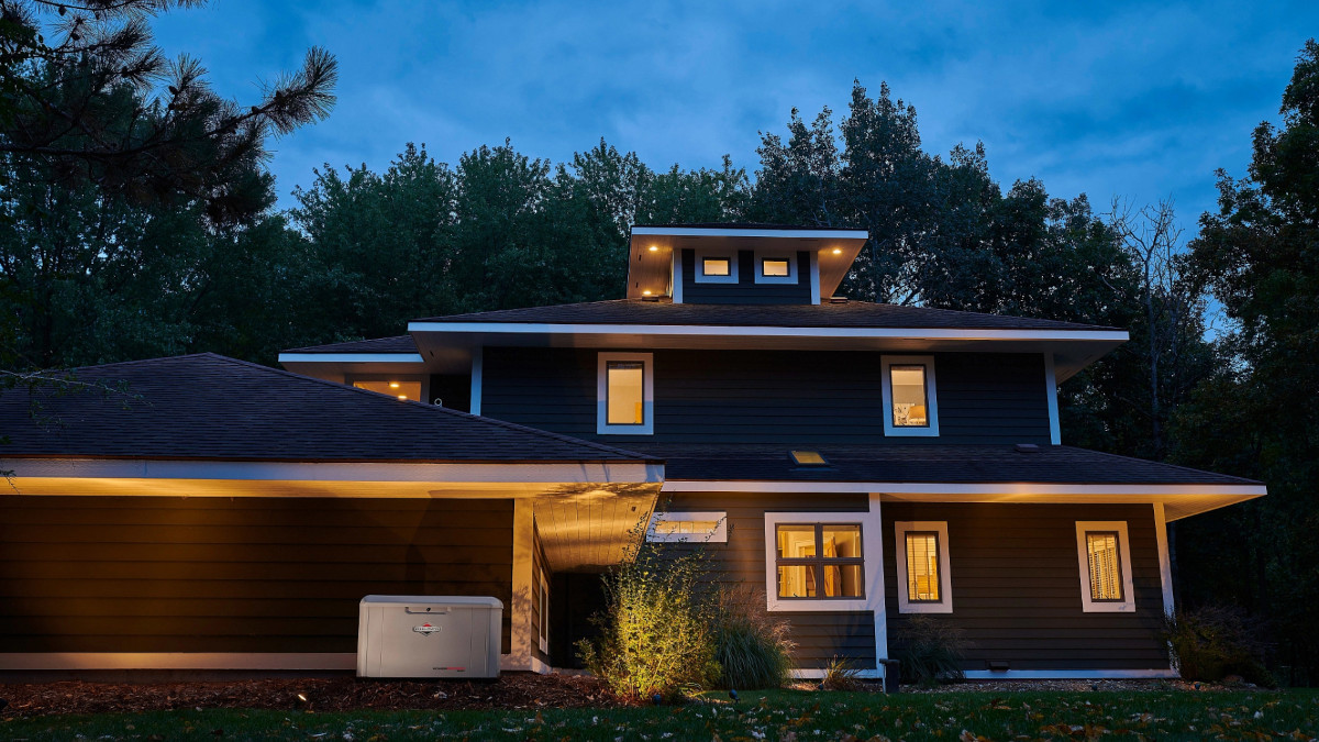 A Home with a Backup Generator at Dusk has Lights