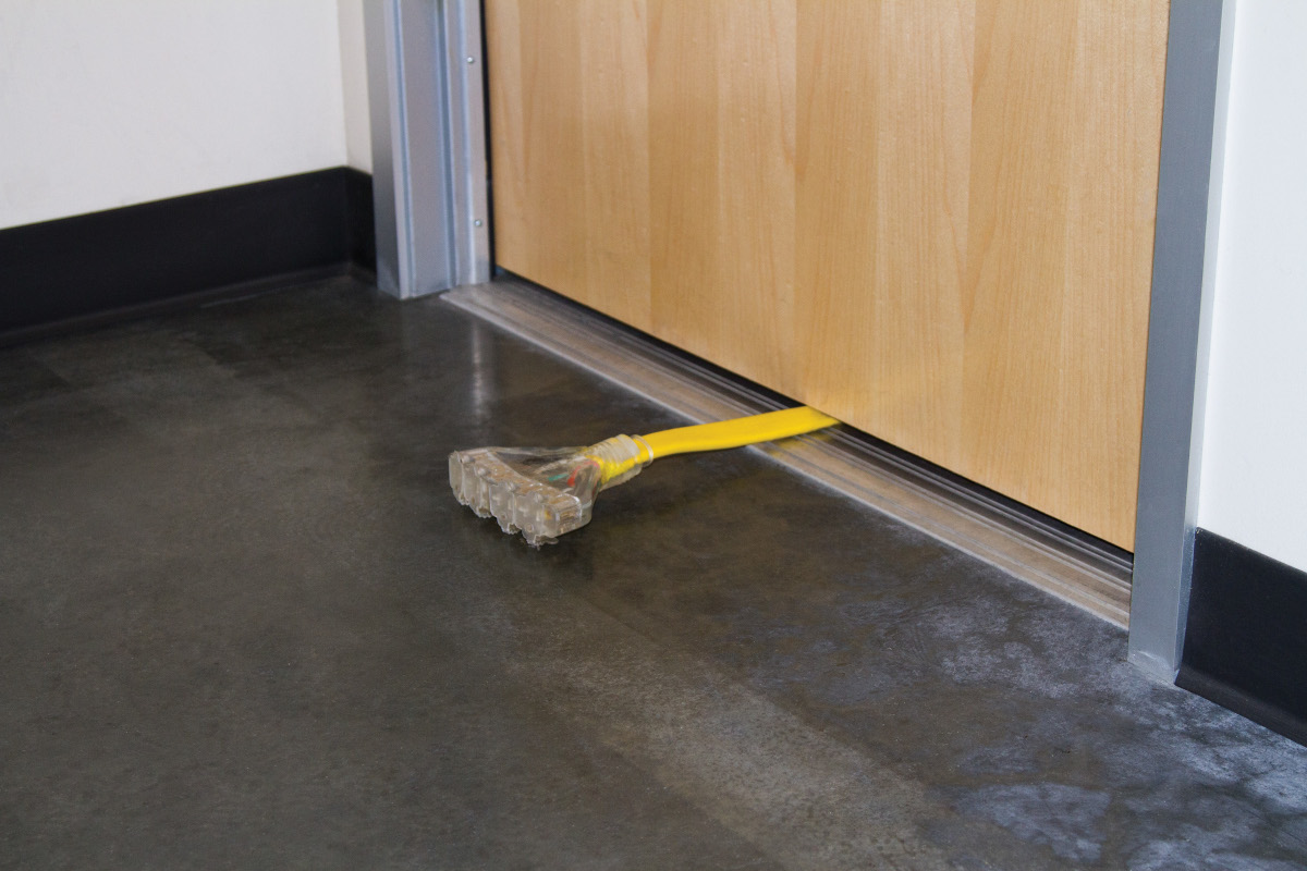 A Generator Power Cord with Four 120V Outlets Under a Door