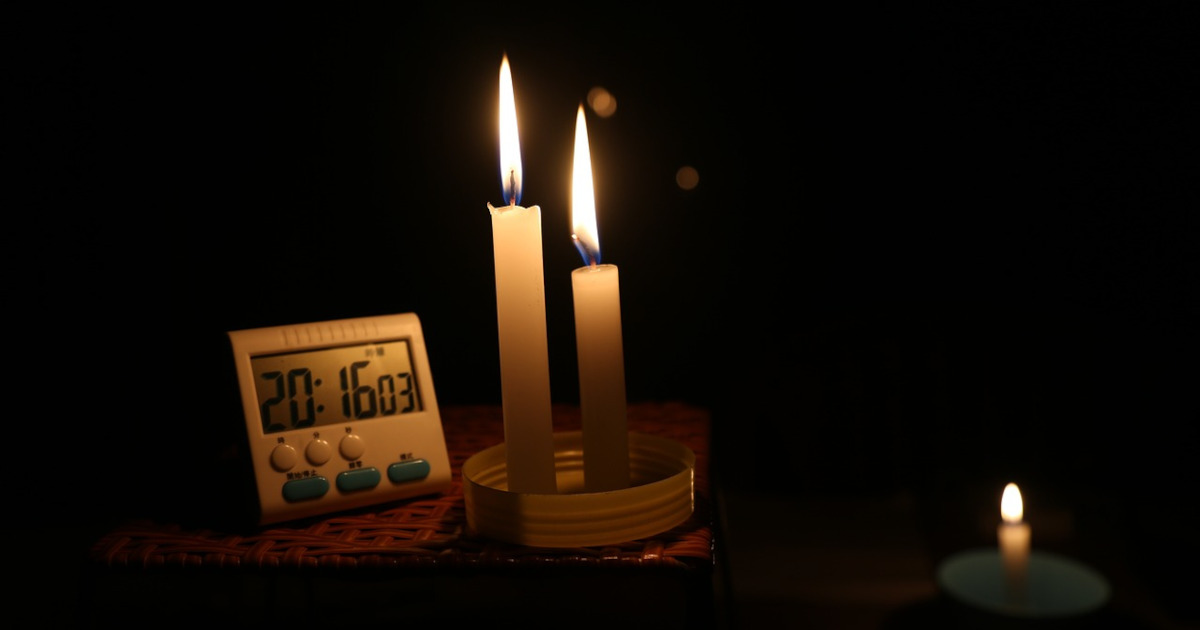 Candles light a table during a power outage. A timer reads more than 20 hours since the power went out.